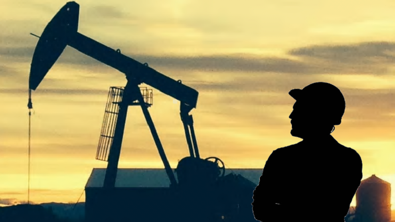 Field engineer beside a pumpjack at sunset